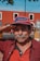 man in red button up shirt wearing black and red fitted cap