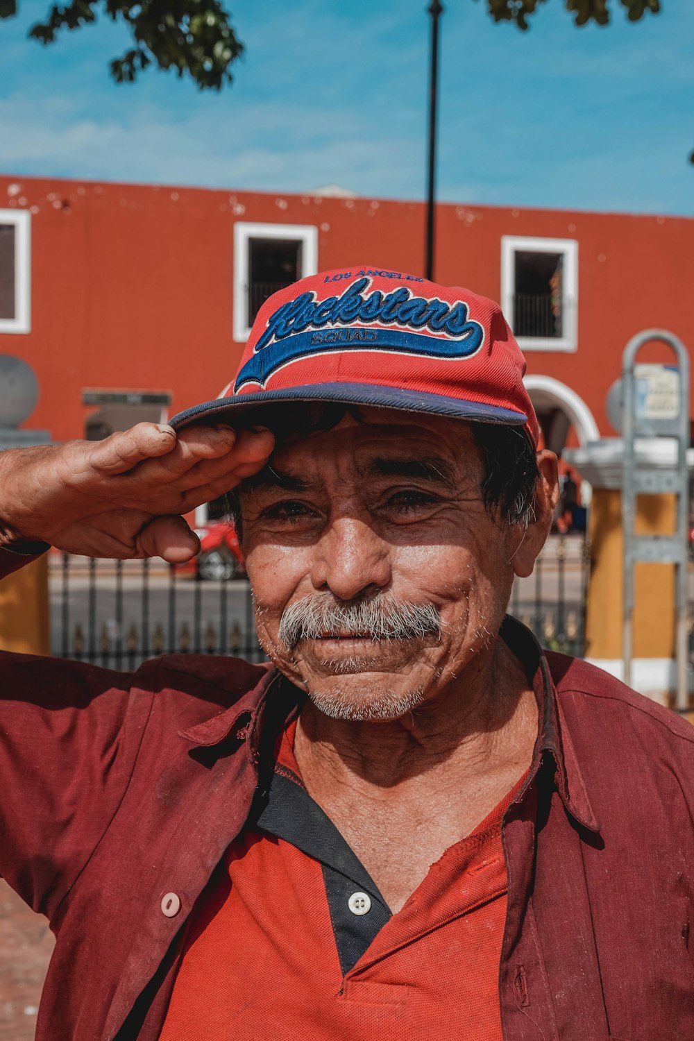 man in red button up shirt wearing black and red fitted cap