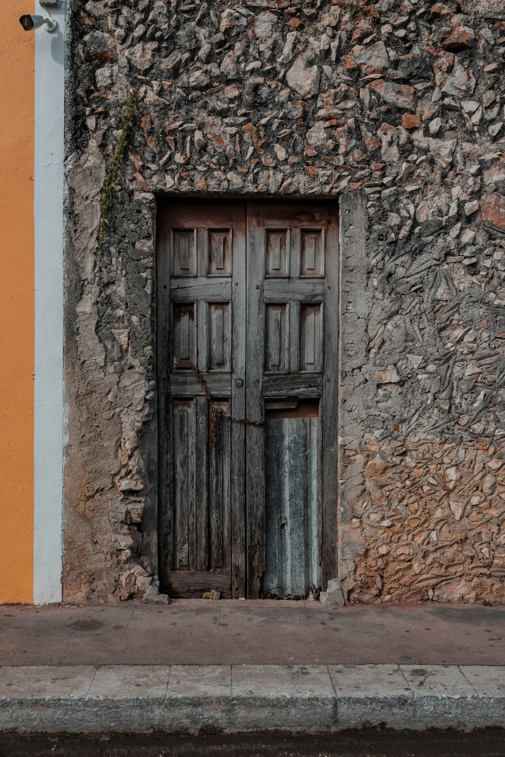 puerta de madera negra sobre pared de hormigón naranja