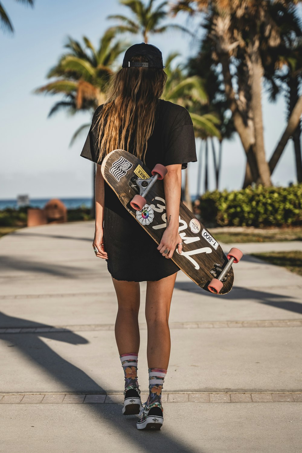 woman in black t-shirt and brown shorts holding skateboard
