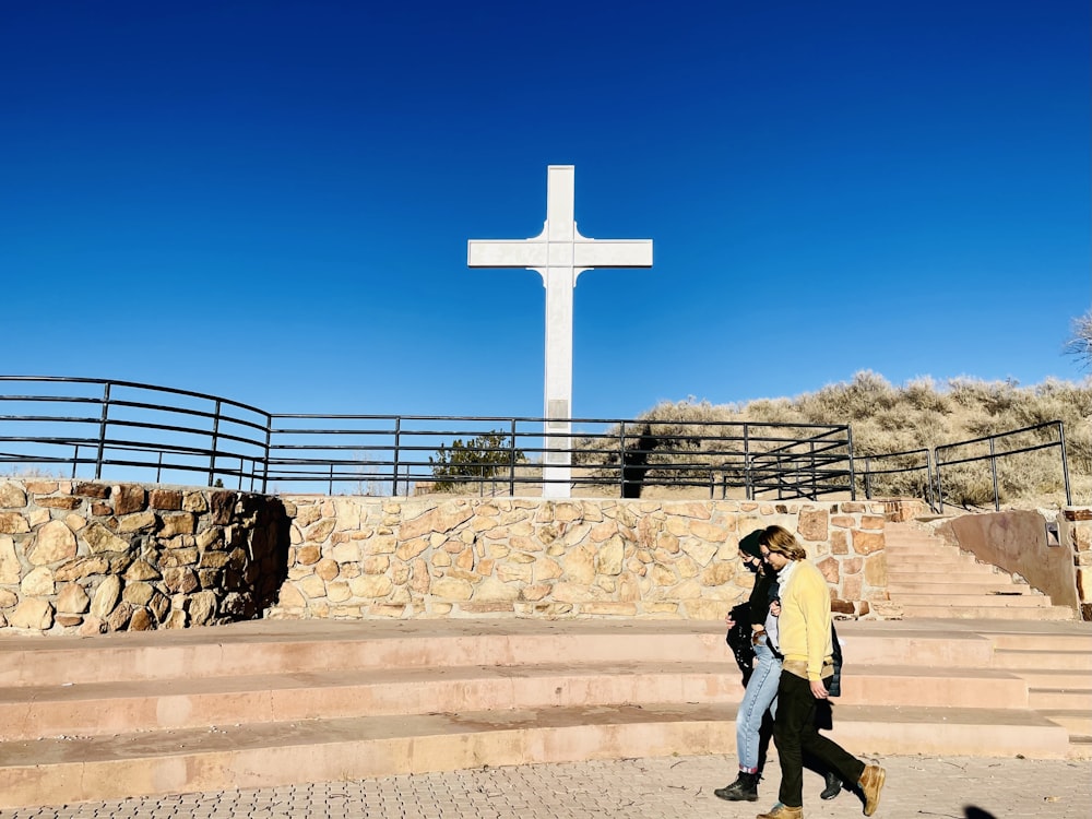 man in gray shirt standing near cross during daytime