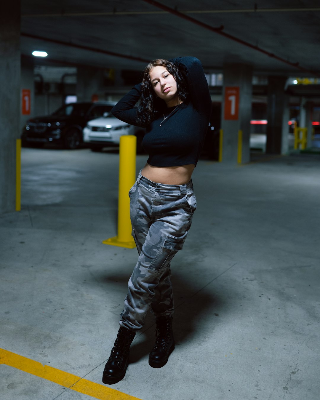 woman in black sports bra and blue denim jeans standing on gray concrete floor