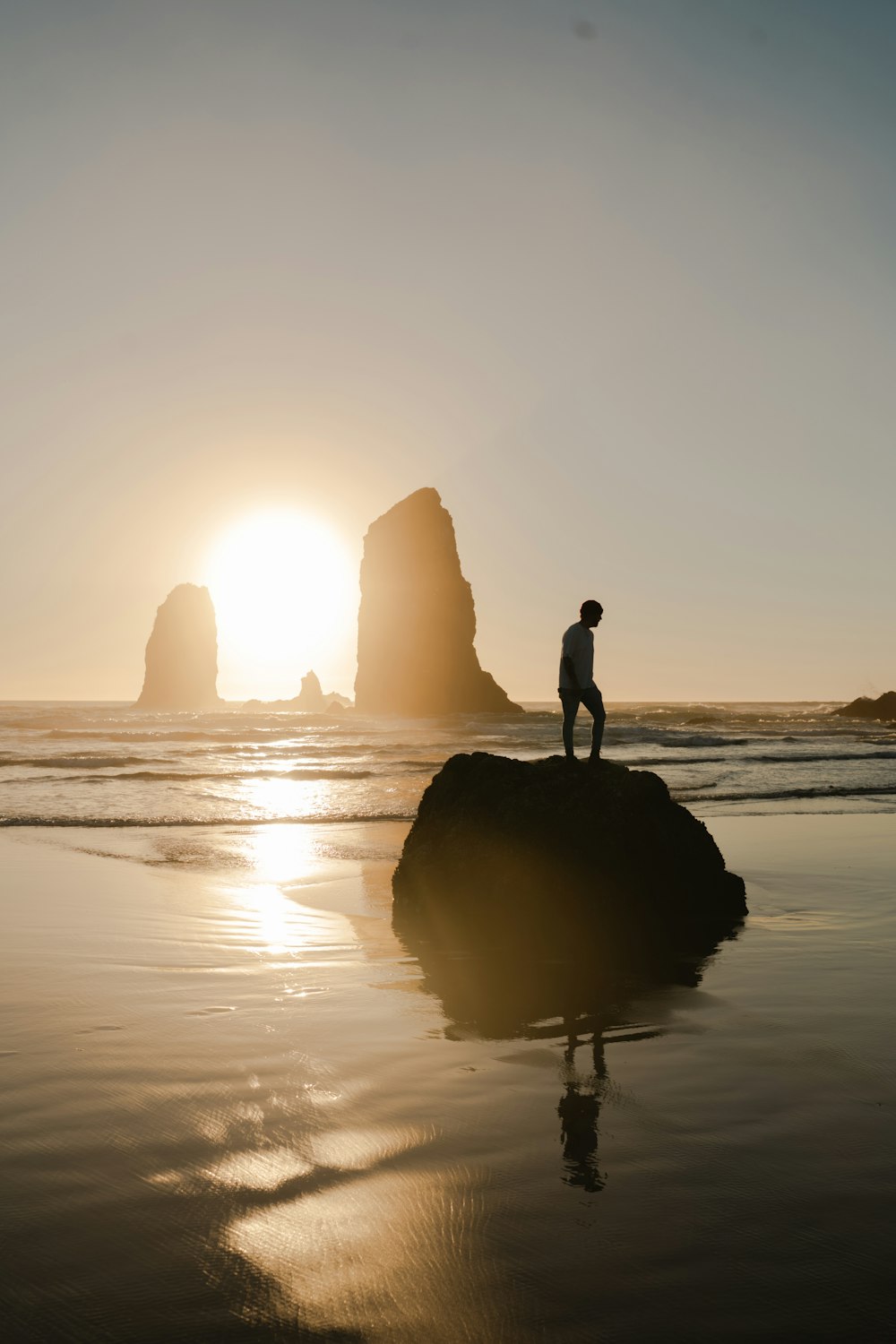 silhouette of man standing on rock near sea during daytime