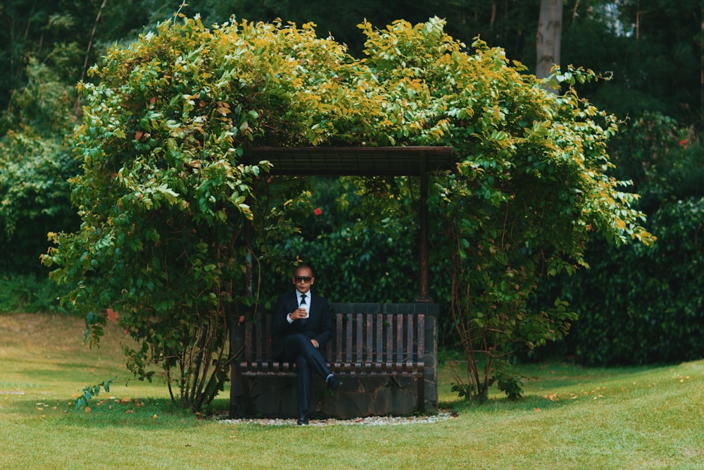 man in black jacket sitting on black wooden bench