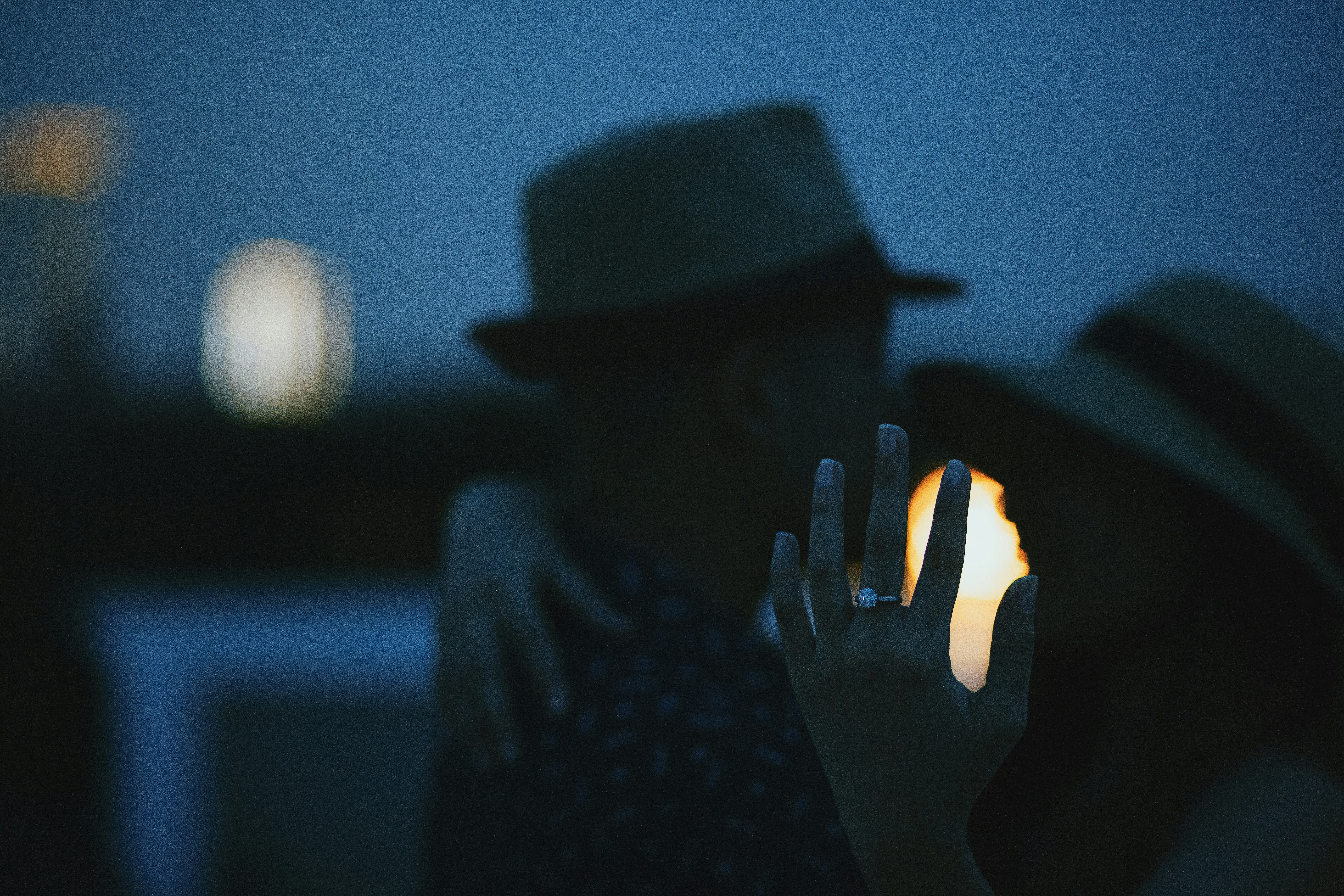 person wearing black hat holding lighted candle