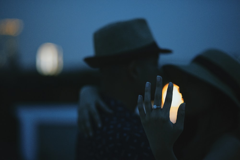 person wearing black hat holding lighted candle