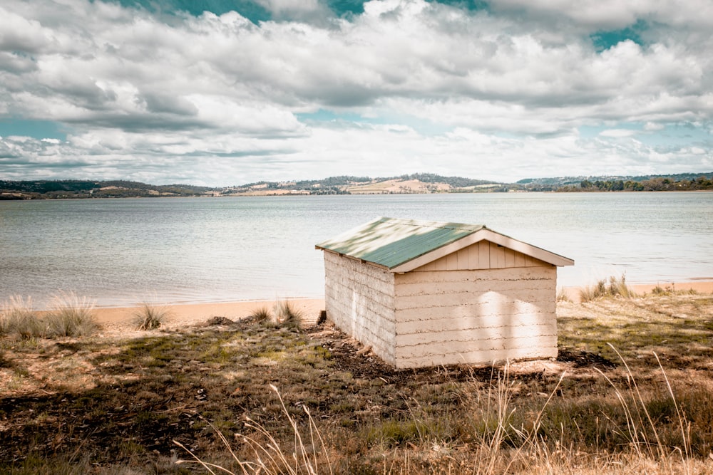 brown wooden house near body of water under white clouds during daytime