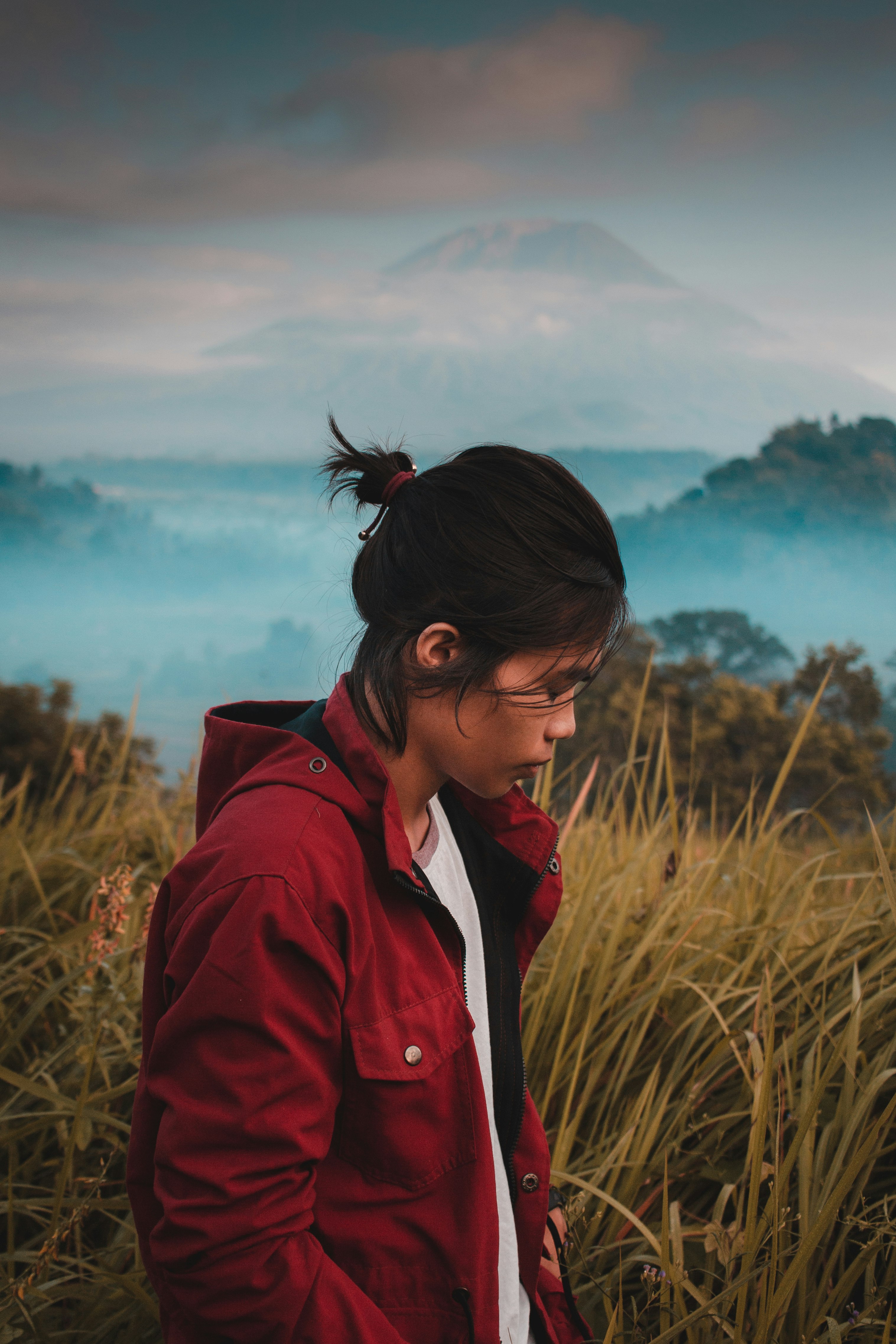 woman in red jacket standing on brown grass field during daytime