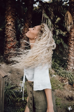 woman in white shirt standing near brown wooden fence during daytime