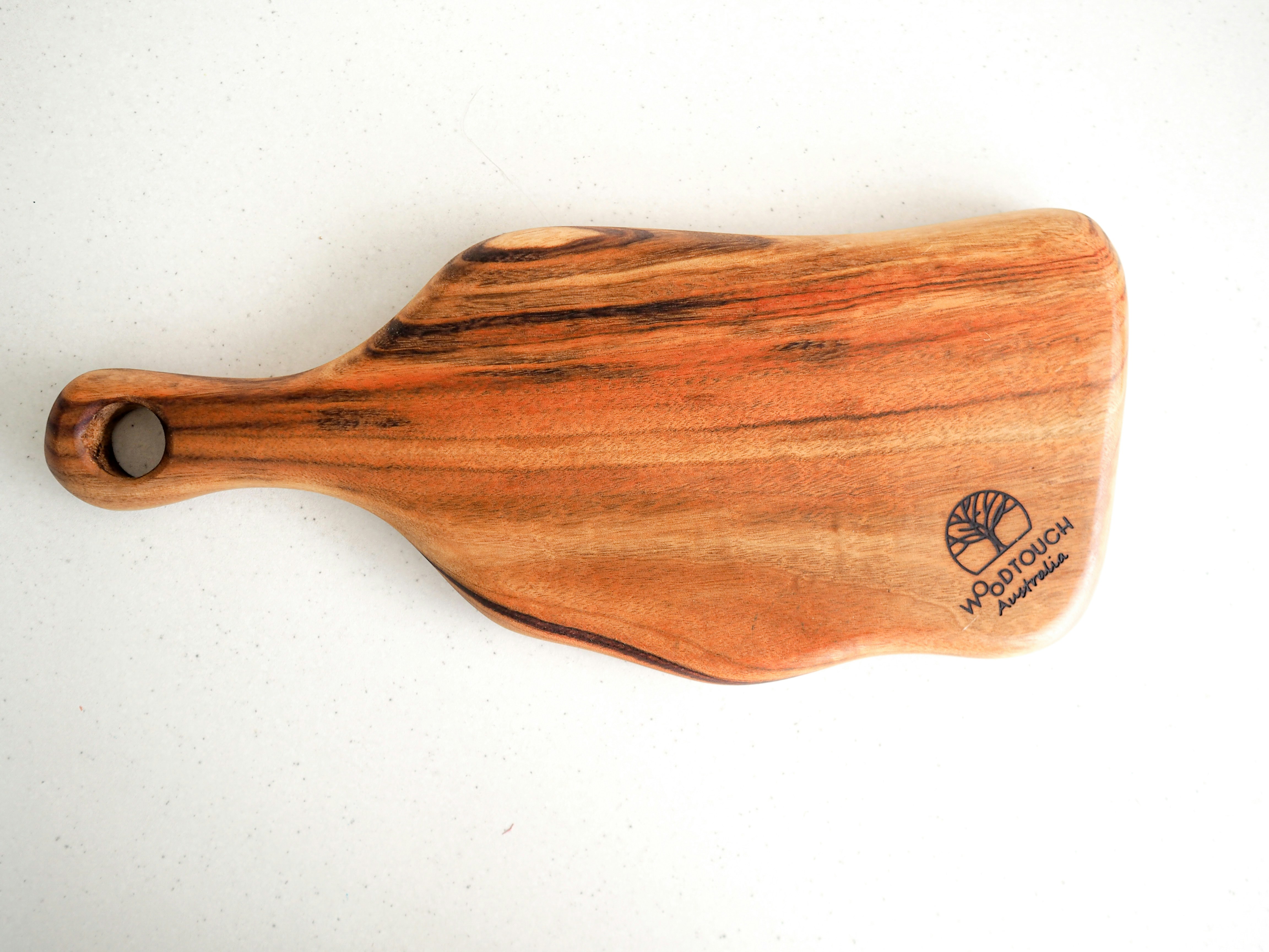 Rectangular bamboo cutting board with handle on clean white kitchen counter