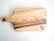 A wooden cutting board with natural wood grain patterns, highlighting darker and lighter streaks. The board has a handle with a hole for hanging. A logo with the text 'WOODTOUCH Australia' is engraved in one corner.