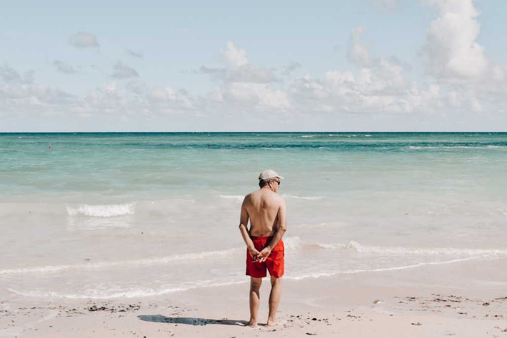 man in red shorts standing on beach during daytime