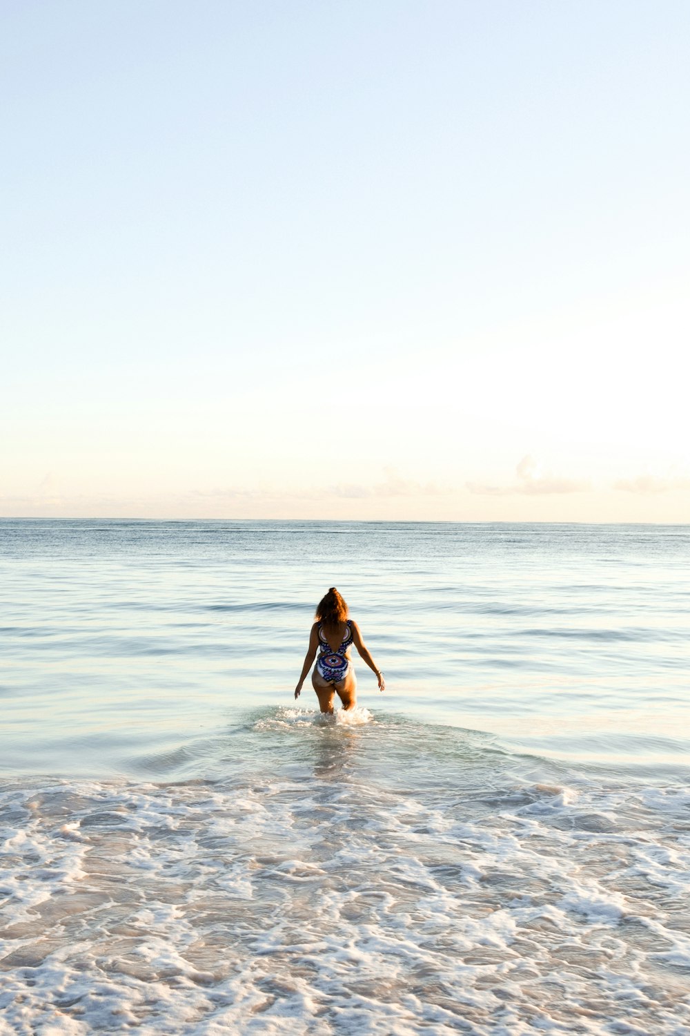 Mujer en bikini negro de pie en la orilla del mar durante el día