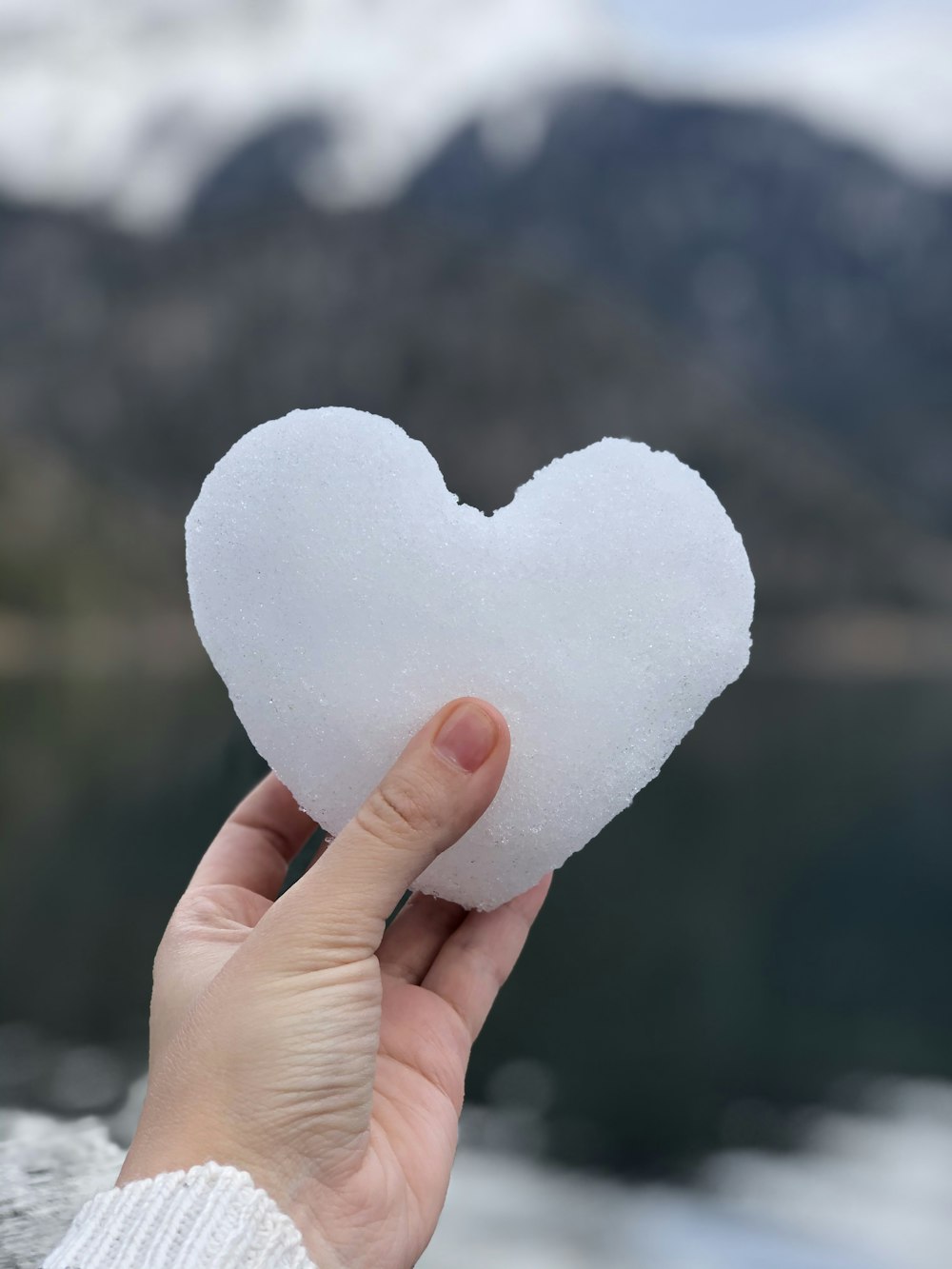 person holding snow covered heart shaped