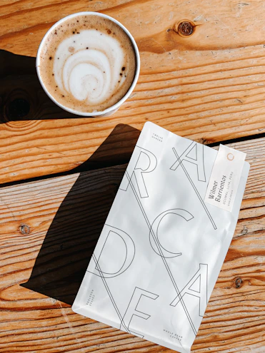 Elegant drip coffee bag resting on a wooden table surrounded by cardamom pods.
