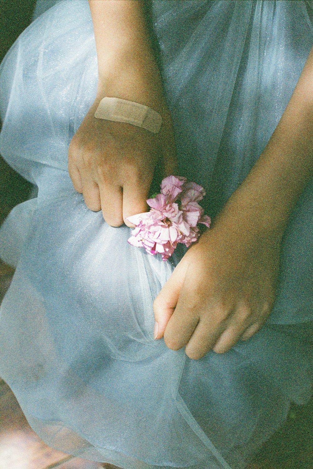 woman in teal dress holding pink flower