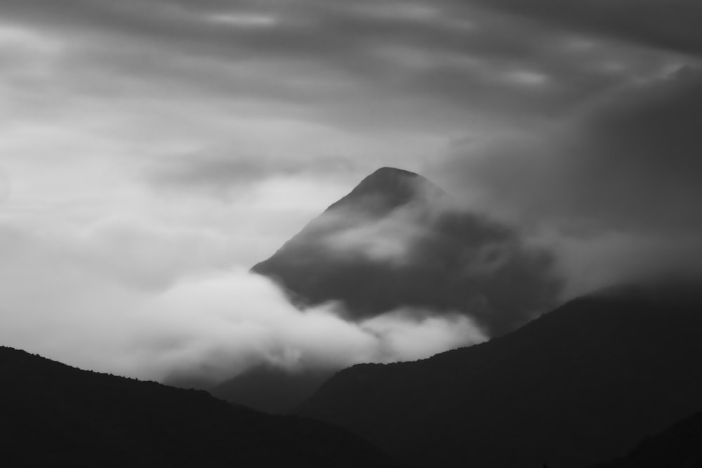 grayscale photo of mountain under cloudy sky