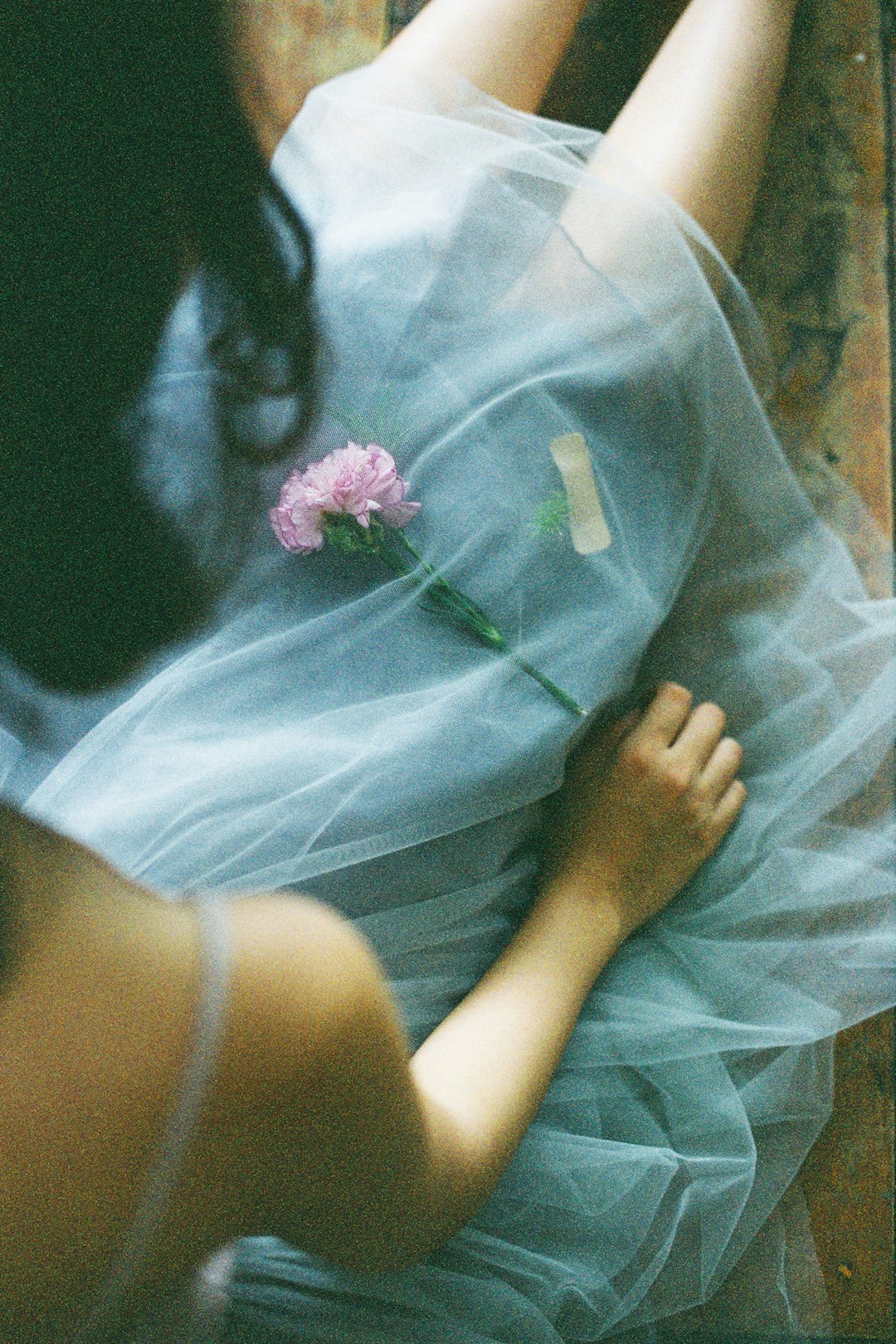 woman in green dress holding pink flower