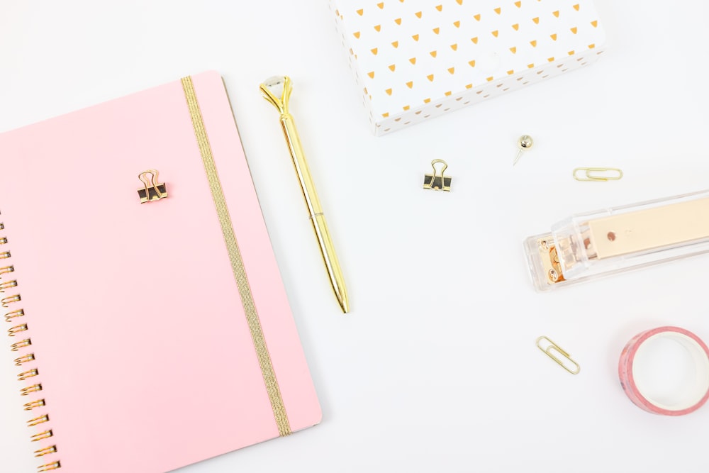 gold pen beside pink book