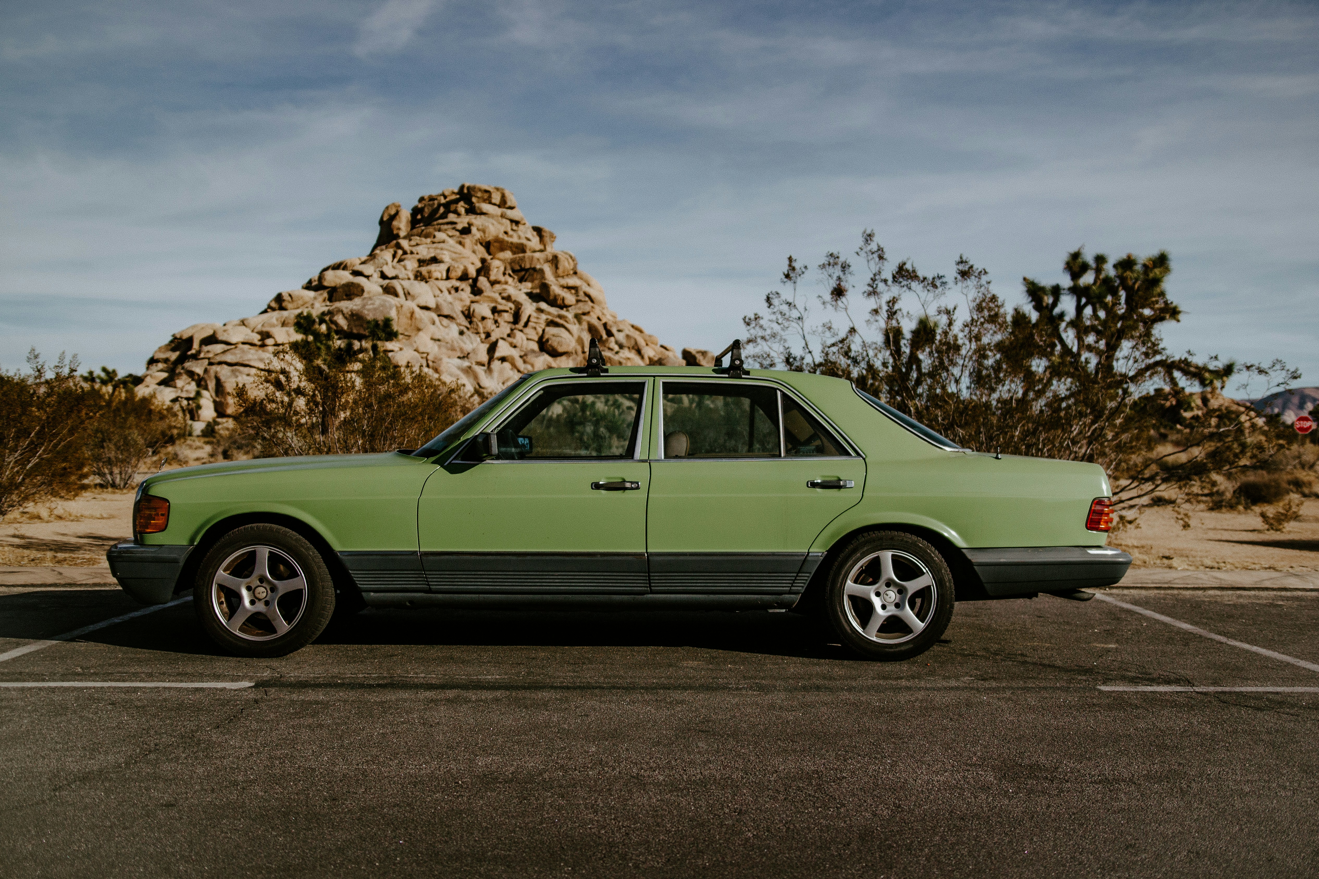 green coupe parked beside brown rock formation during daytime