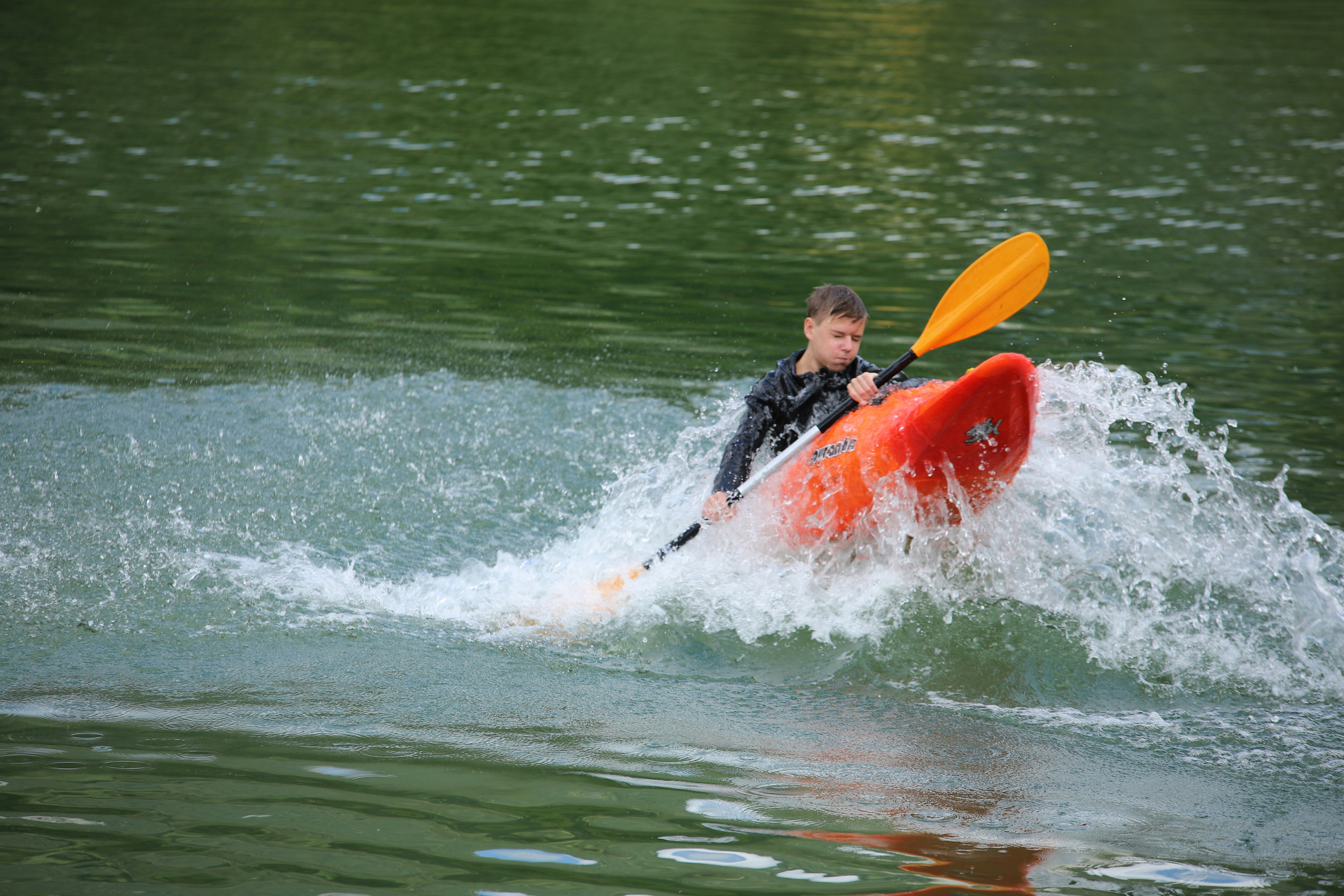 man in black and red jacket riding red kayak on water during daytime