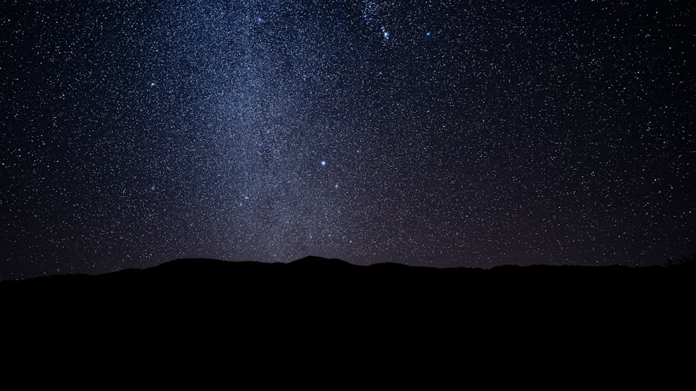 silhouette of mountain under starry night