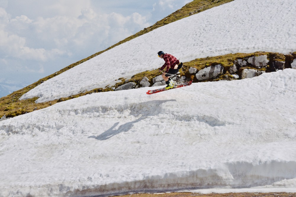 person in red jacket riding red snow board during daytime