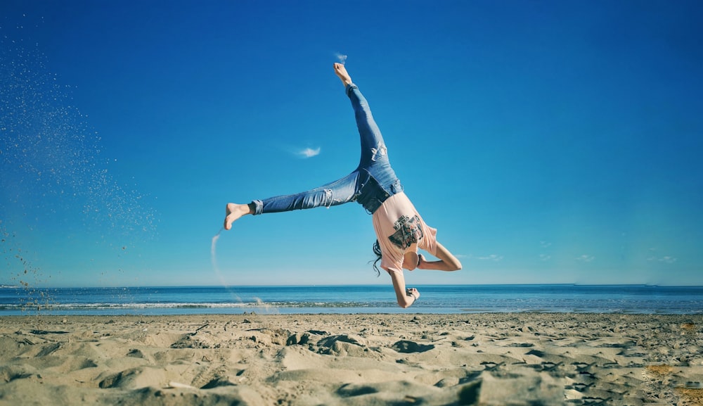 femme en jean bleu saut sur la plage pendant la journée