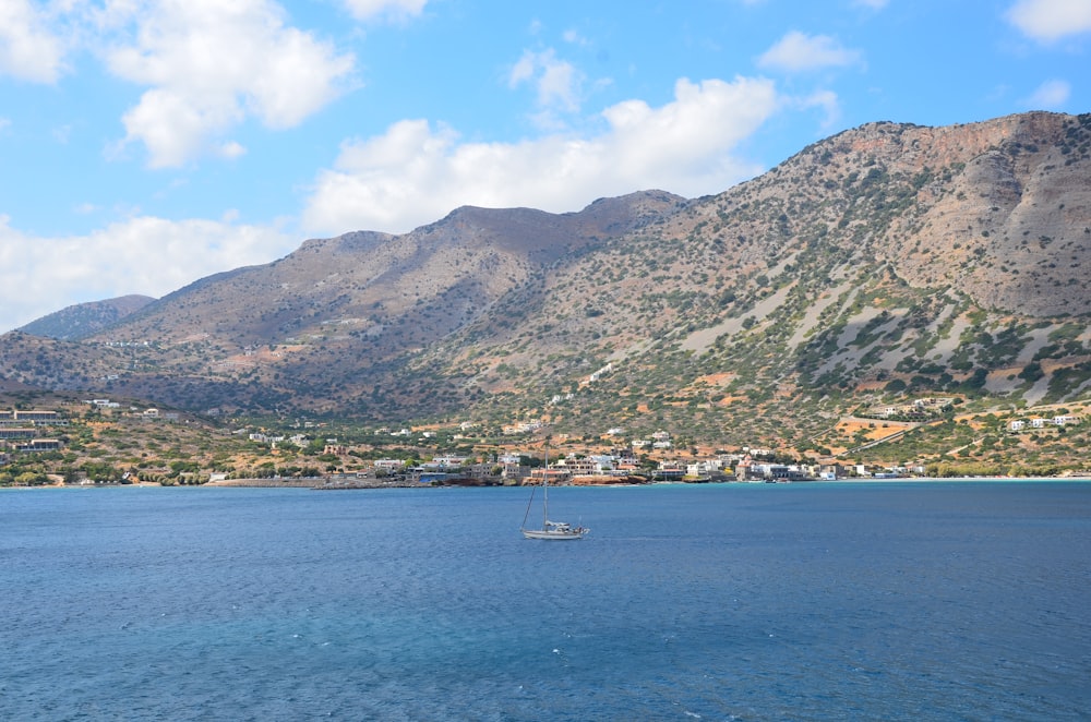 white boat on sea near mountain during daytime