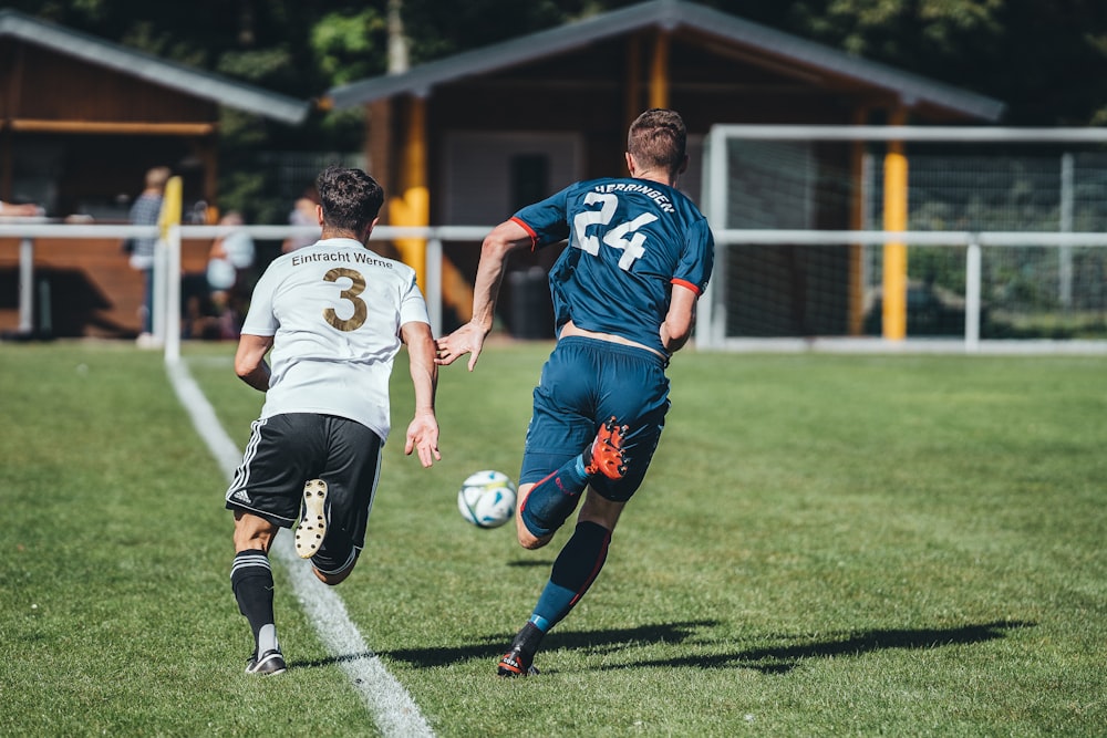 2 men playing soccer on green grass field during daytime