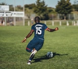 man in blue and white jersey shirt playing soccer during daytime