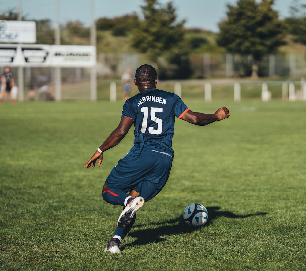 昼間にサッカーをする青と白のジャージシャツを着た男性