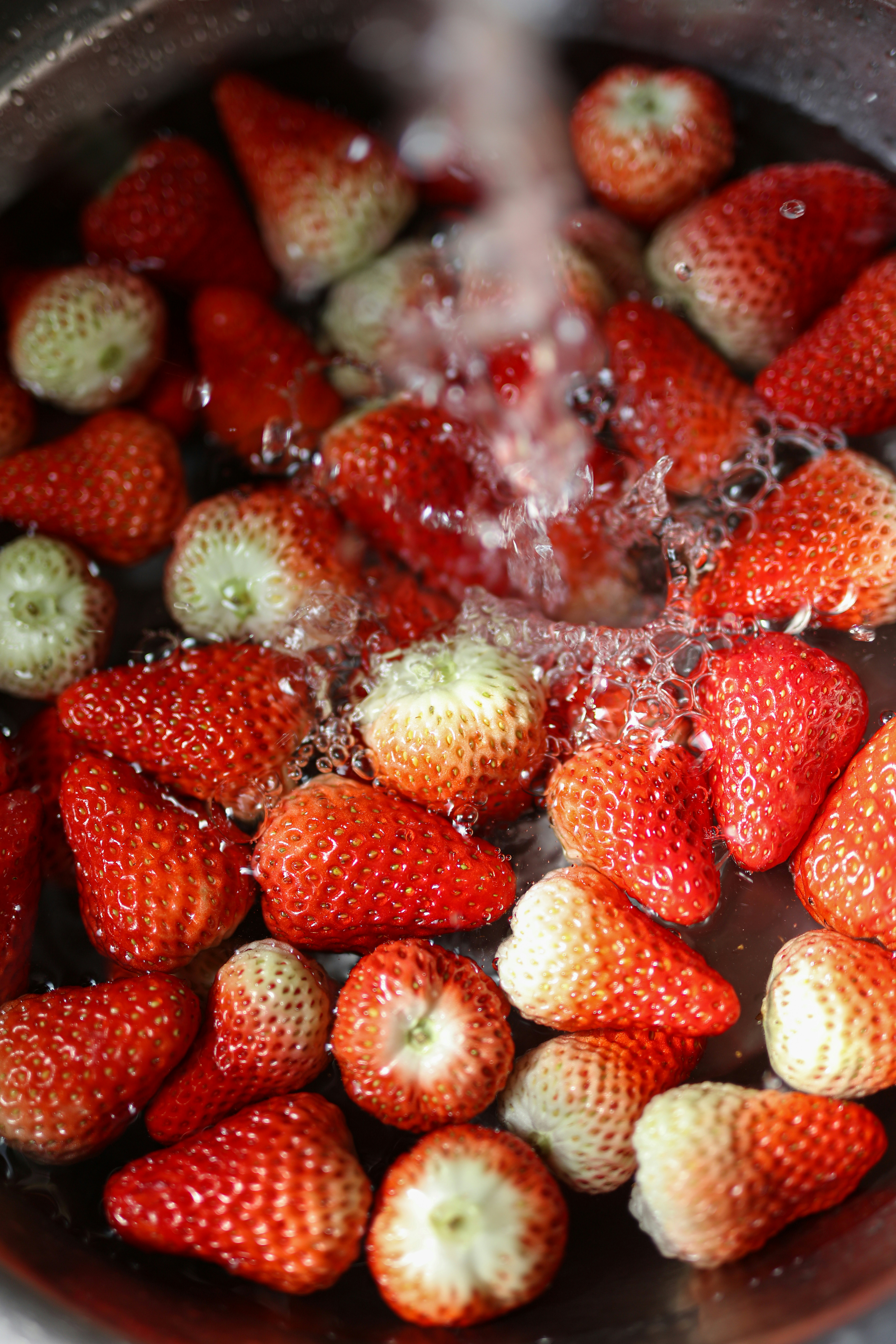 Fresh tropical fruits being rinsed with clean water, glistening in bright light