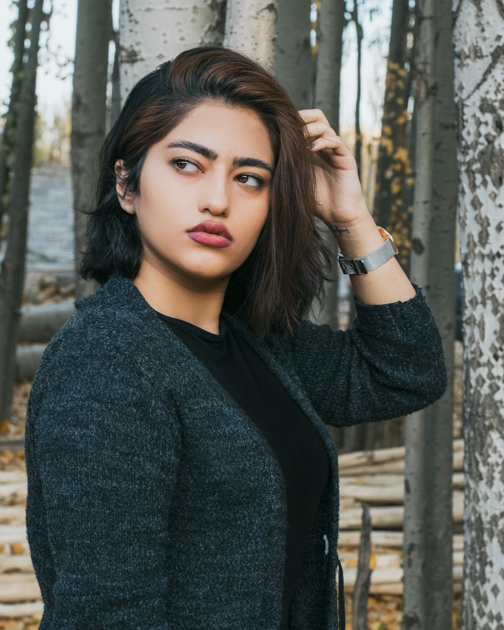 woman in black sweater standing near brown wooden fence during daytime