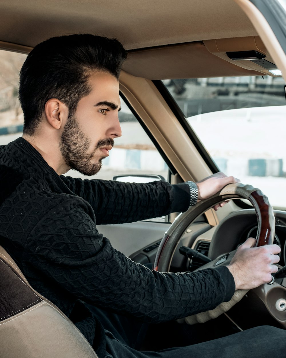 man in black and gray striped long sleeve shirt driving car during daytime