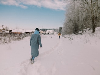 man in gray jacket walking on snow covered ground during daytime