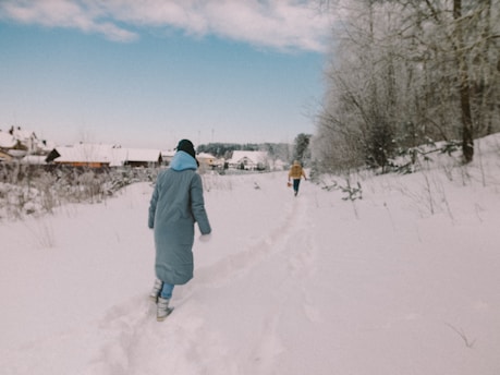 man in gray jacket walking on snow covered ground during daytime