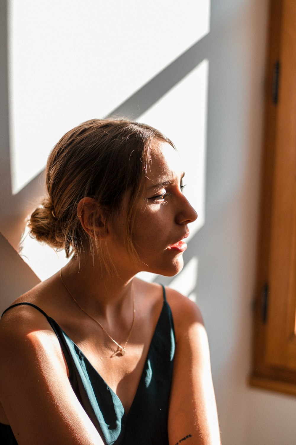 woman in blue tank top looking at the window