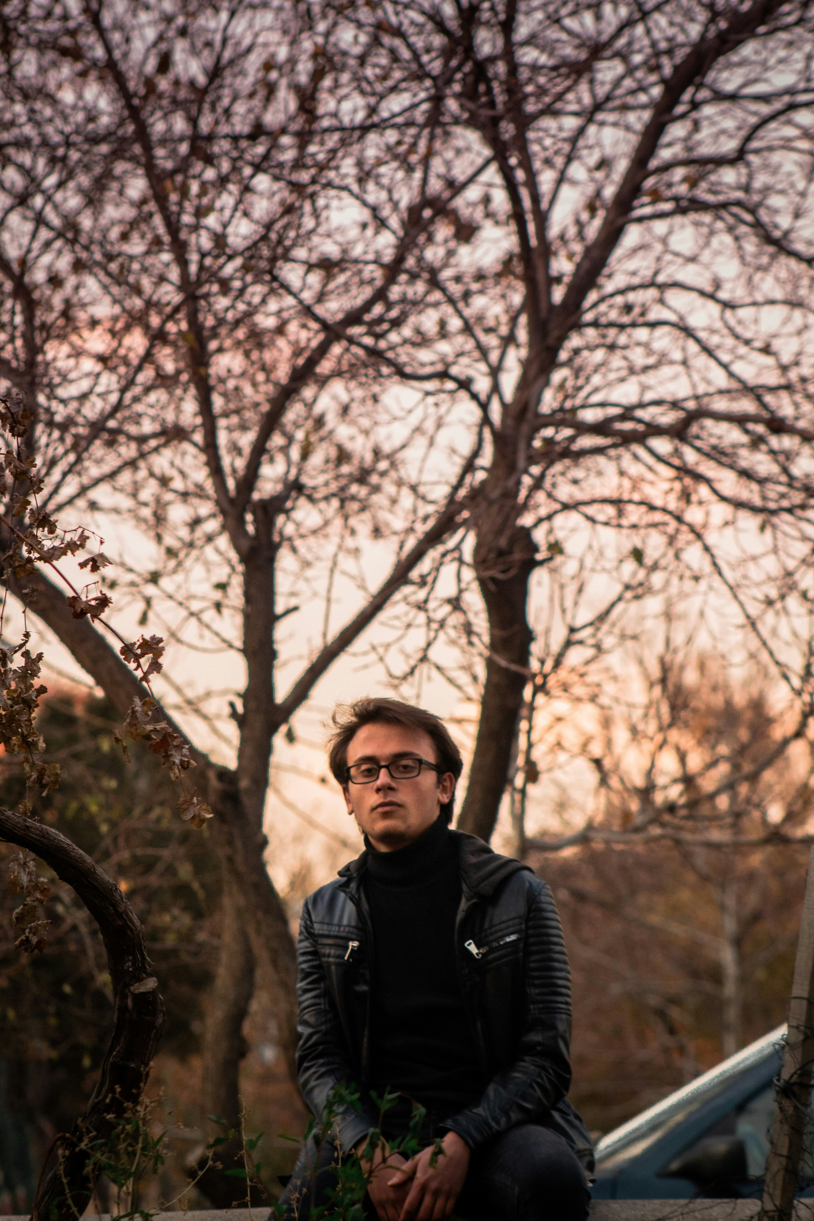 man in black jacket standing near brown bare tree during daytime
