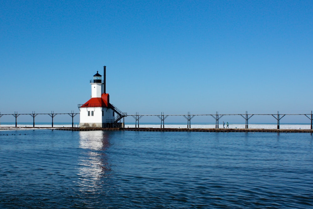 white and red lighthouse on dock under blue sky during daytime