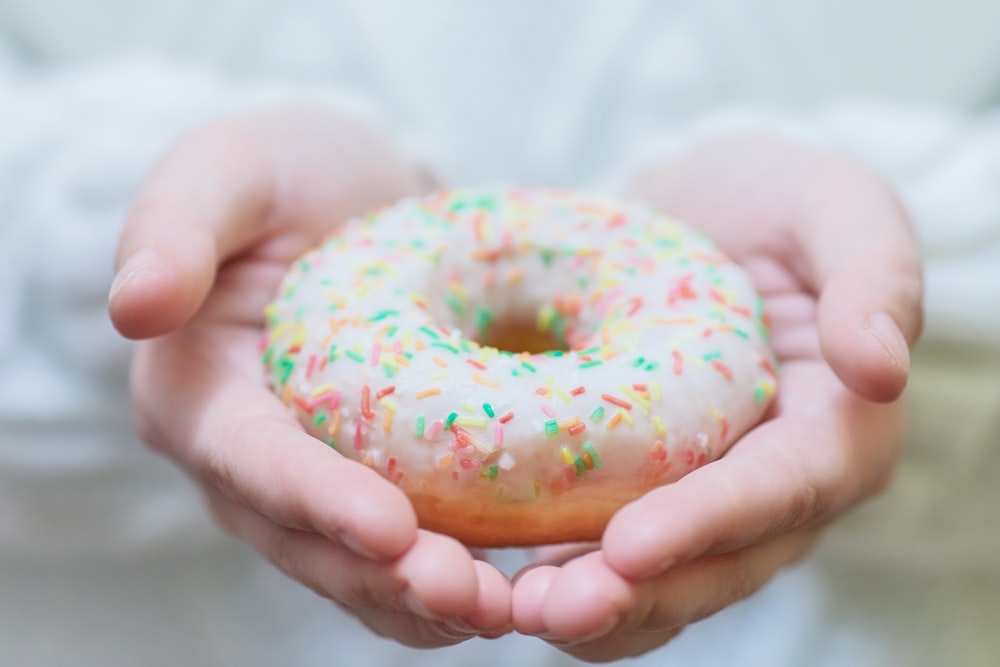person holding doughnut with sprinkles