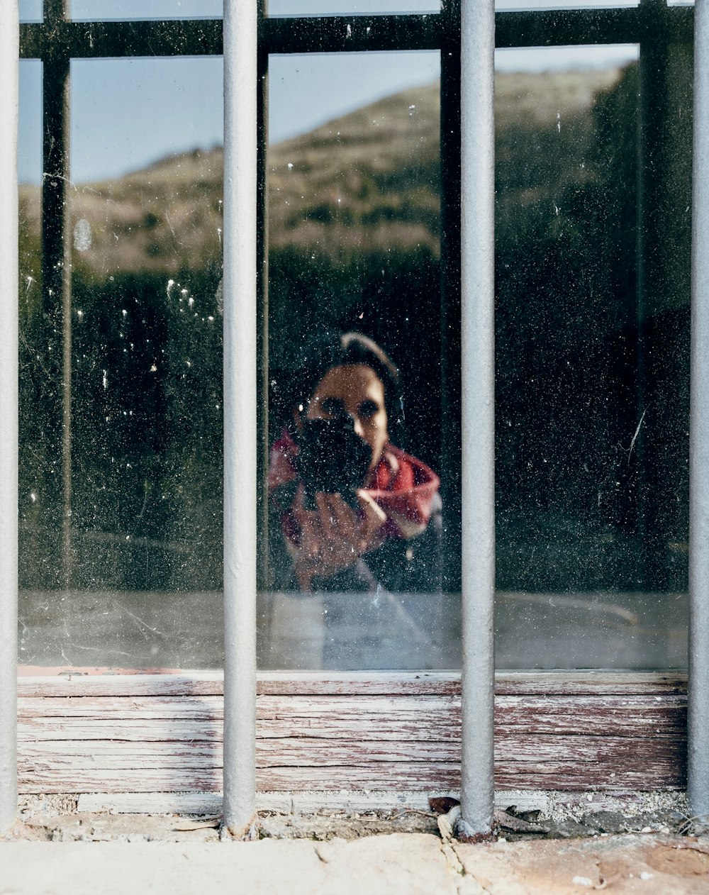 Muchacha con chaqueta roja y blanca de pie junto a la ventana