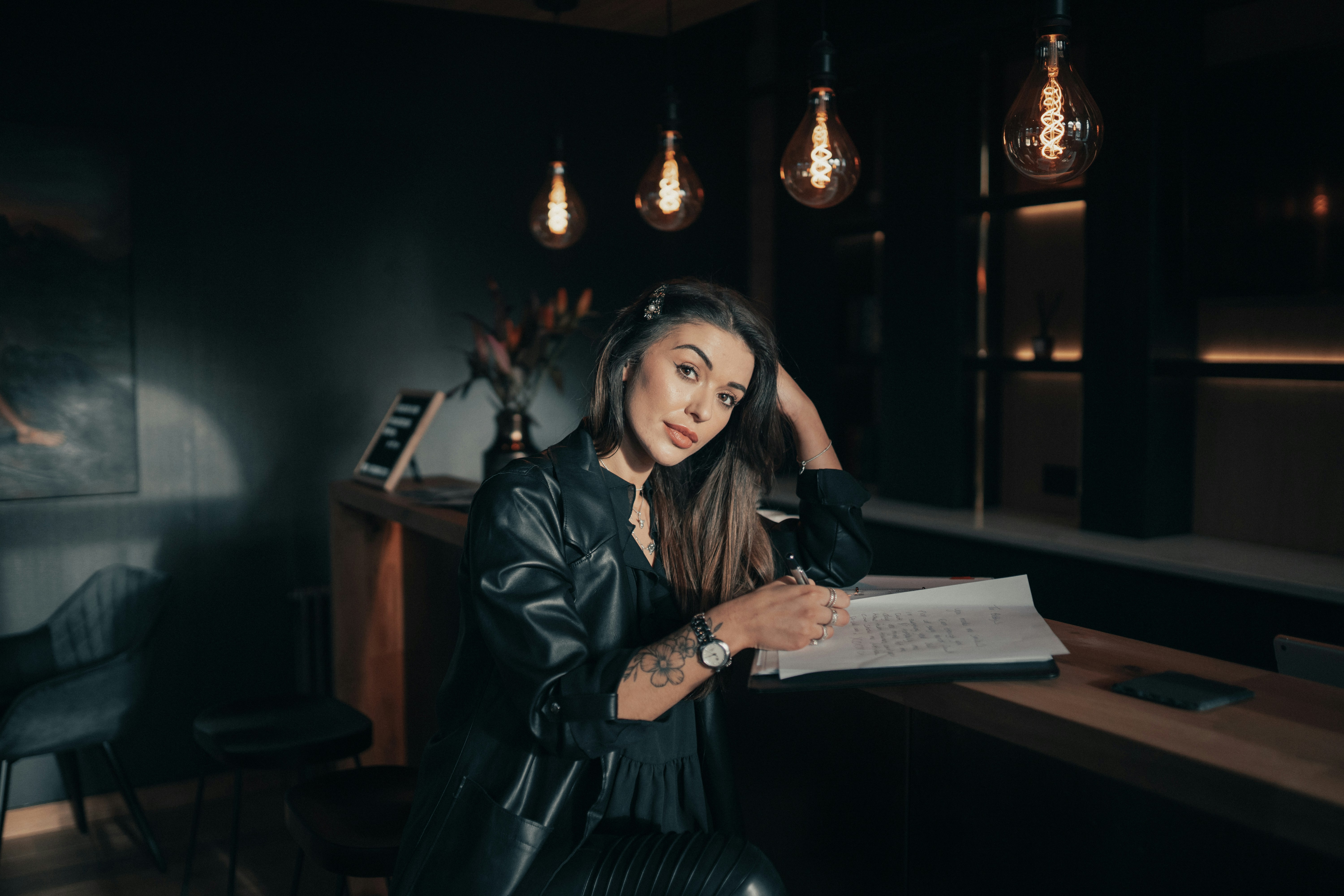 woman in black leather jacket holding white printer paper