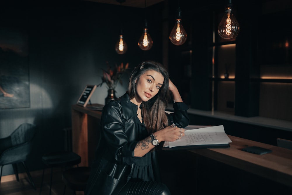 woman in black leather jacket holding white printer paper