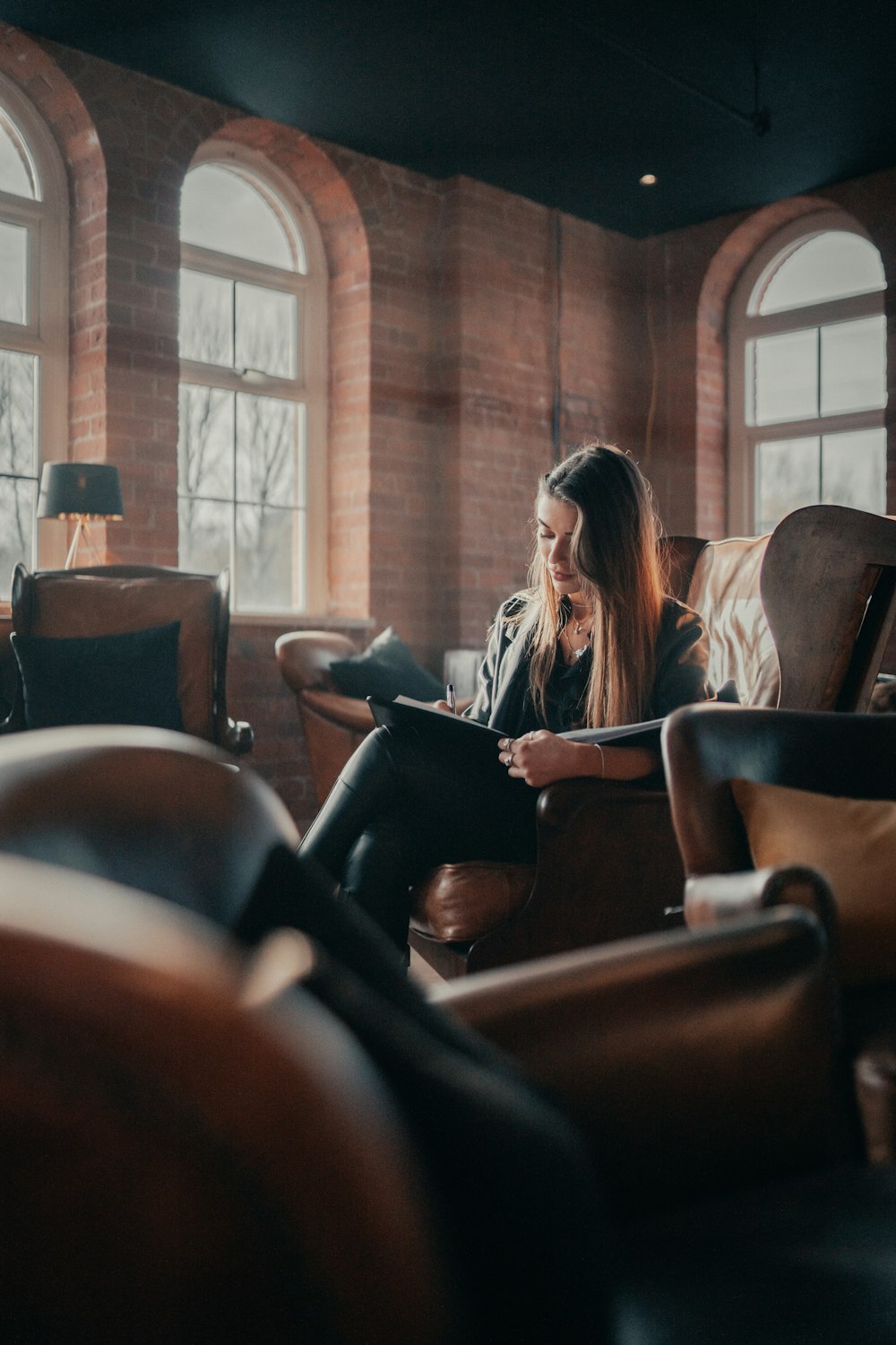 woman in black shirt sitting on brown leather chair