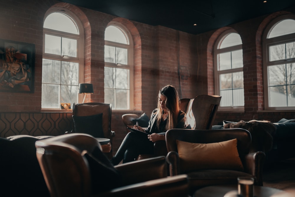 2 women sitting on brown leather sofa chairs