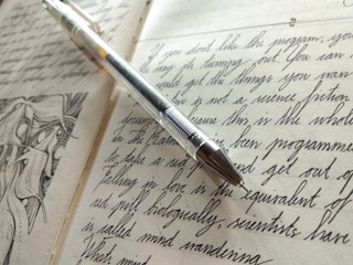 An artistic image of an open diary with handwritten notes and a pen.