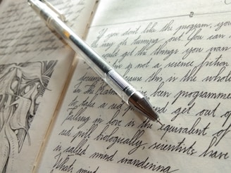 An artistic image of an open diary with handwritten notes and a pen.