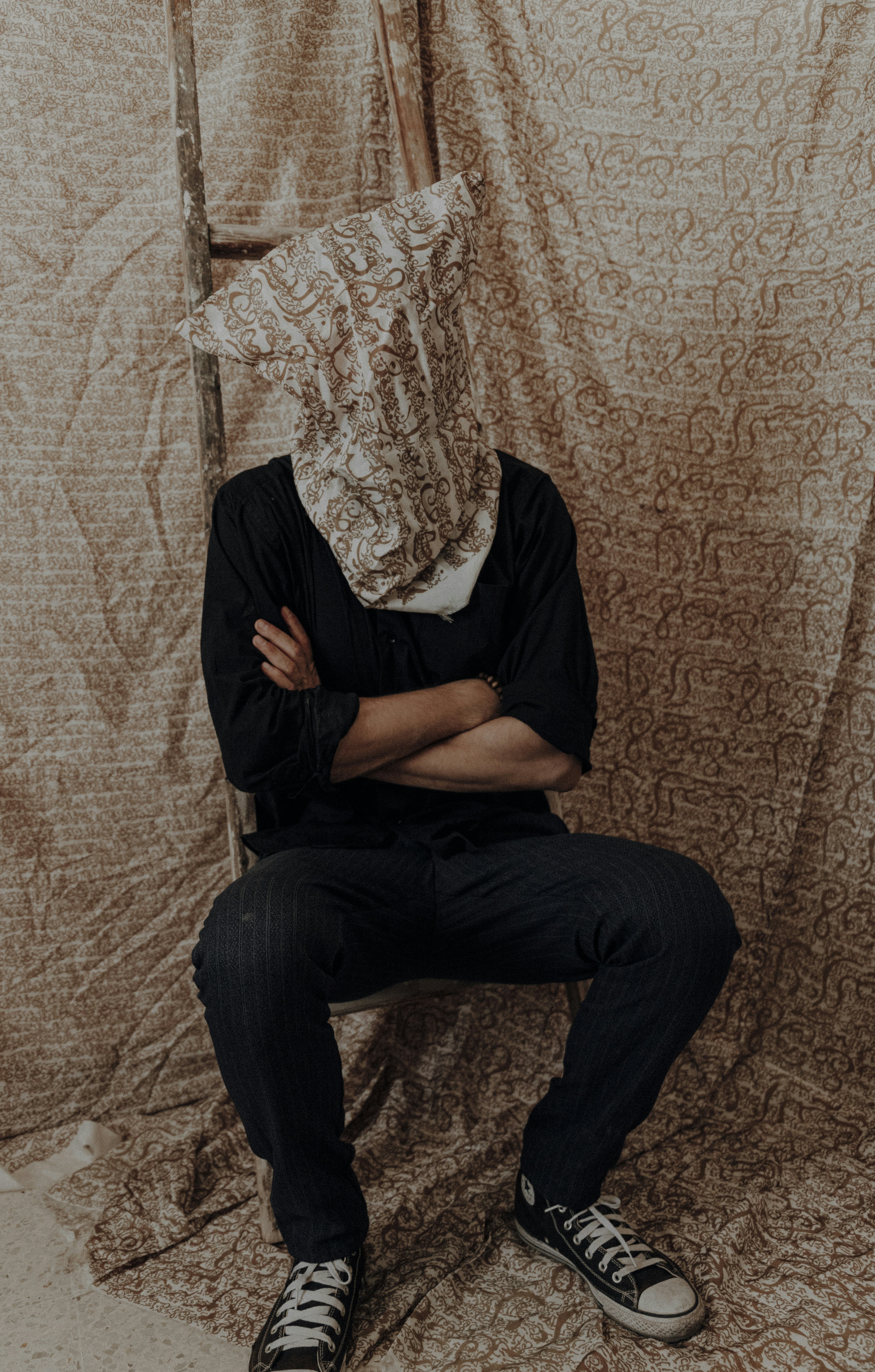Hombre con camisa negra y jeans de mezclilla azul sentado en una silla de madera marrón