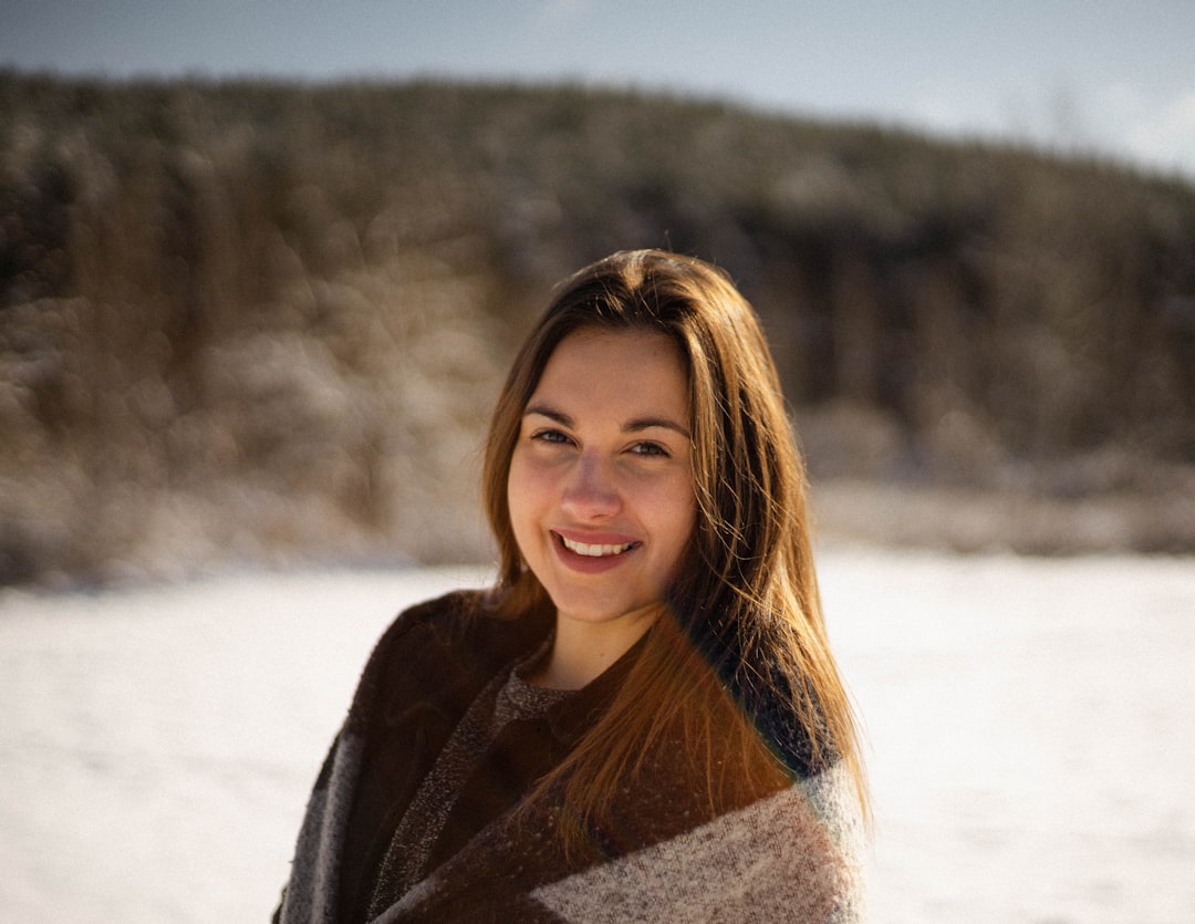 woman in black and white coat standing on snow covered ground during daytime